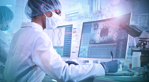 Masked female researcher in lab working at desktop
