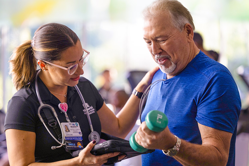 therapist with tablet monitoring patient using light weights