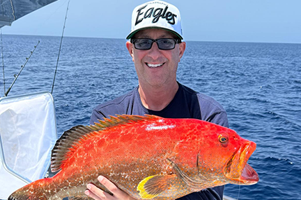 Scott proudly holding a yellowfin grouper he caught during a fishing trip.