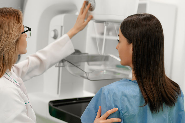 A healthcare professional guiding a patient during a breast imaging exam